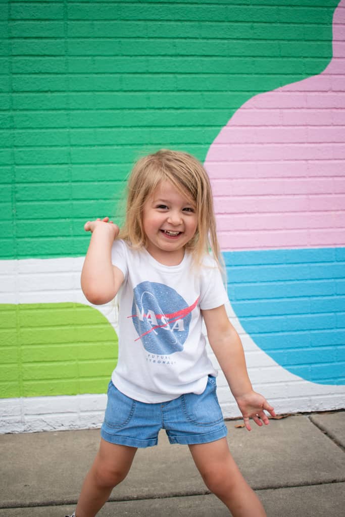 Girl standing in front of one of the many colorful murals in Miami, Oklahoma.