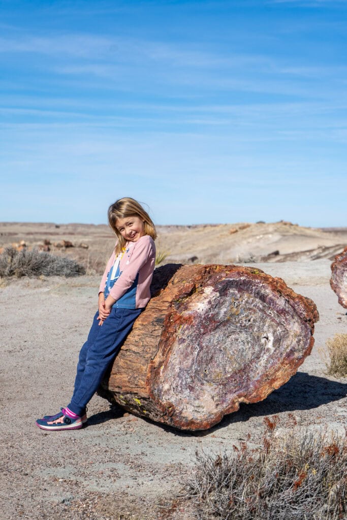 Girl Posing with Large Petrified Log Along the Crystal Forest Trail
