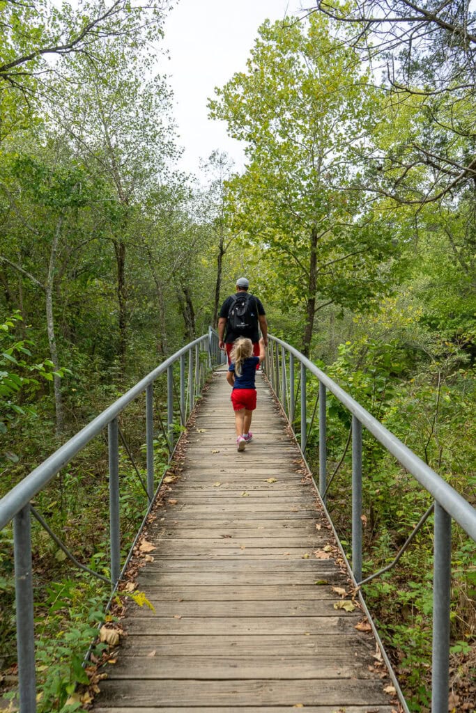 Man with child hiking across a bridge at Robbers Cave State Park