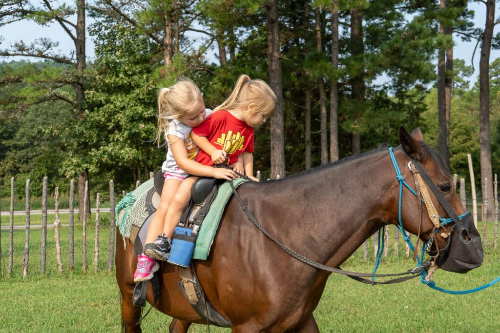 Two girls riding a horse at the Robbers Cave Riding Stables