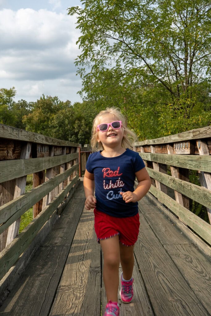 Girl in sunglasses walking along the boardwalk of the outdoor classroom trail at Robbers Cave State Park
