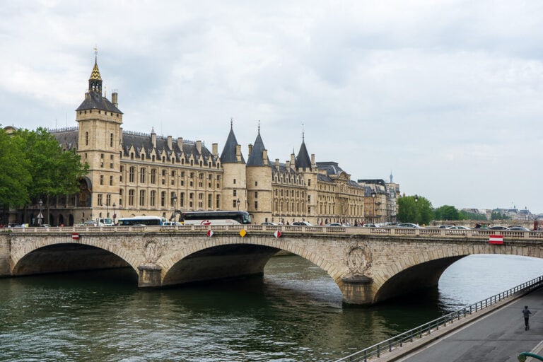 View across the Seine river of the Conciergerie building with cars going across the bridge. We saw this during our day exploring Paris and eating at some of the best cafes in Paris.