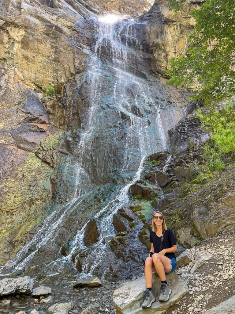 Woman sitting at the base of Bridal Veil Falls along the Spearfish Canyon Scenic Byway in South Dakota